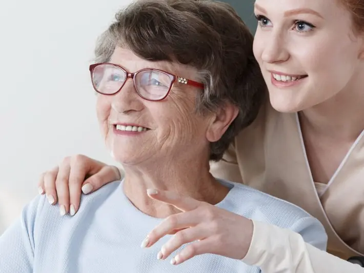 A carer gently comforting an older woman with a hand on her shoulder
